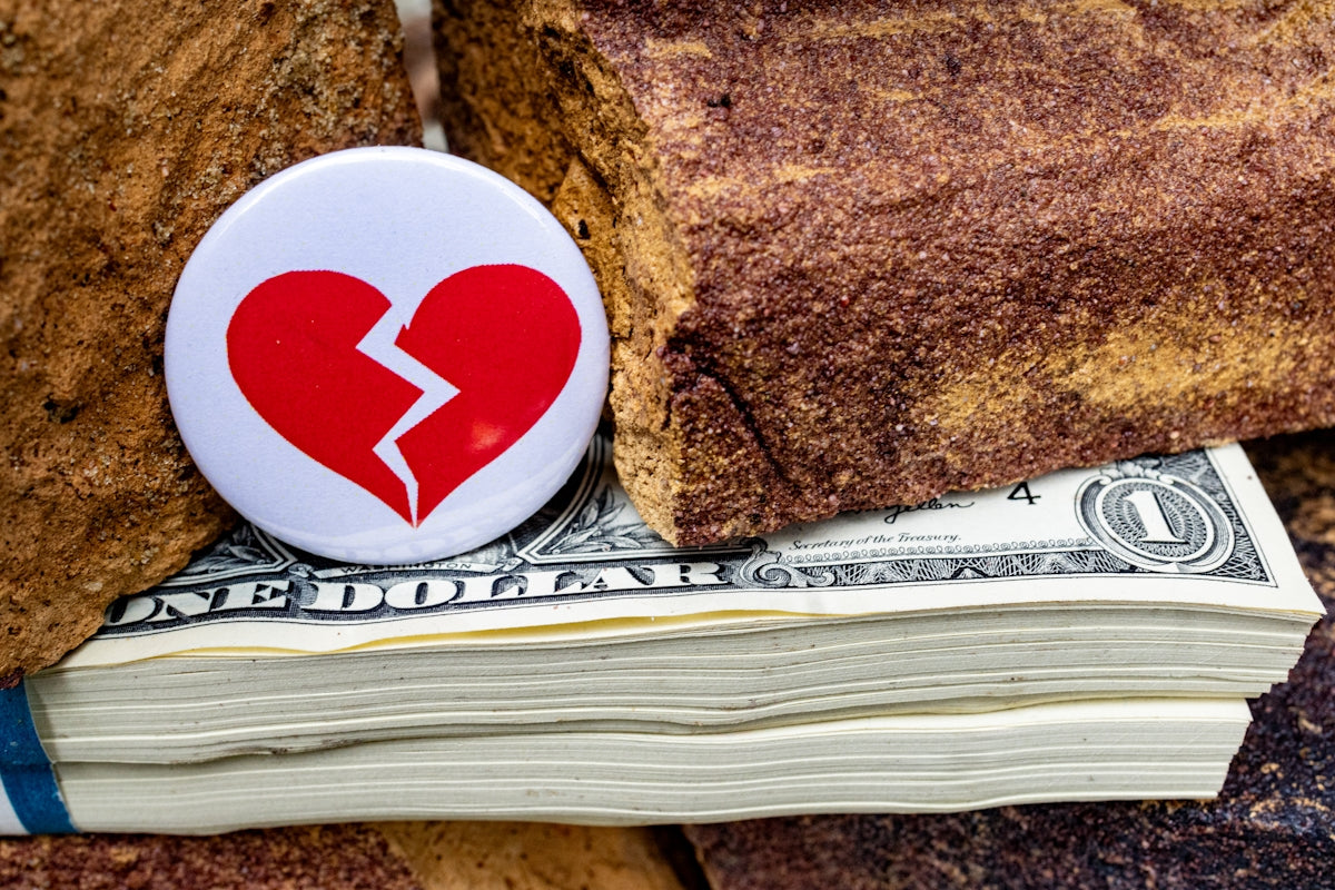A broken heart on top of a stack of money